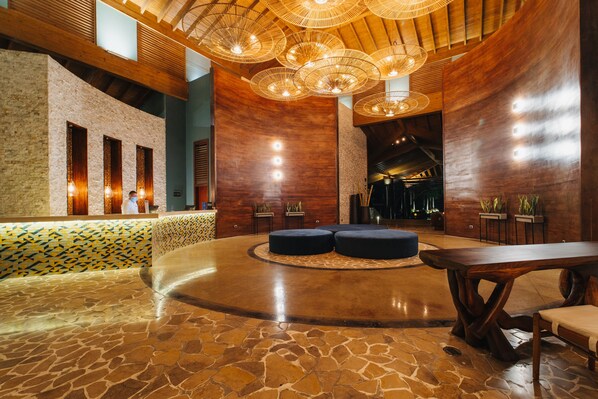 A lobby with a stone floor, wooden accents, and a large wooden table.