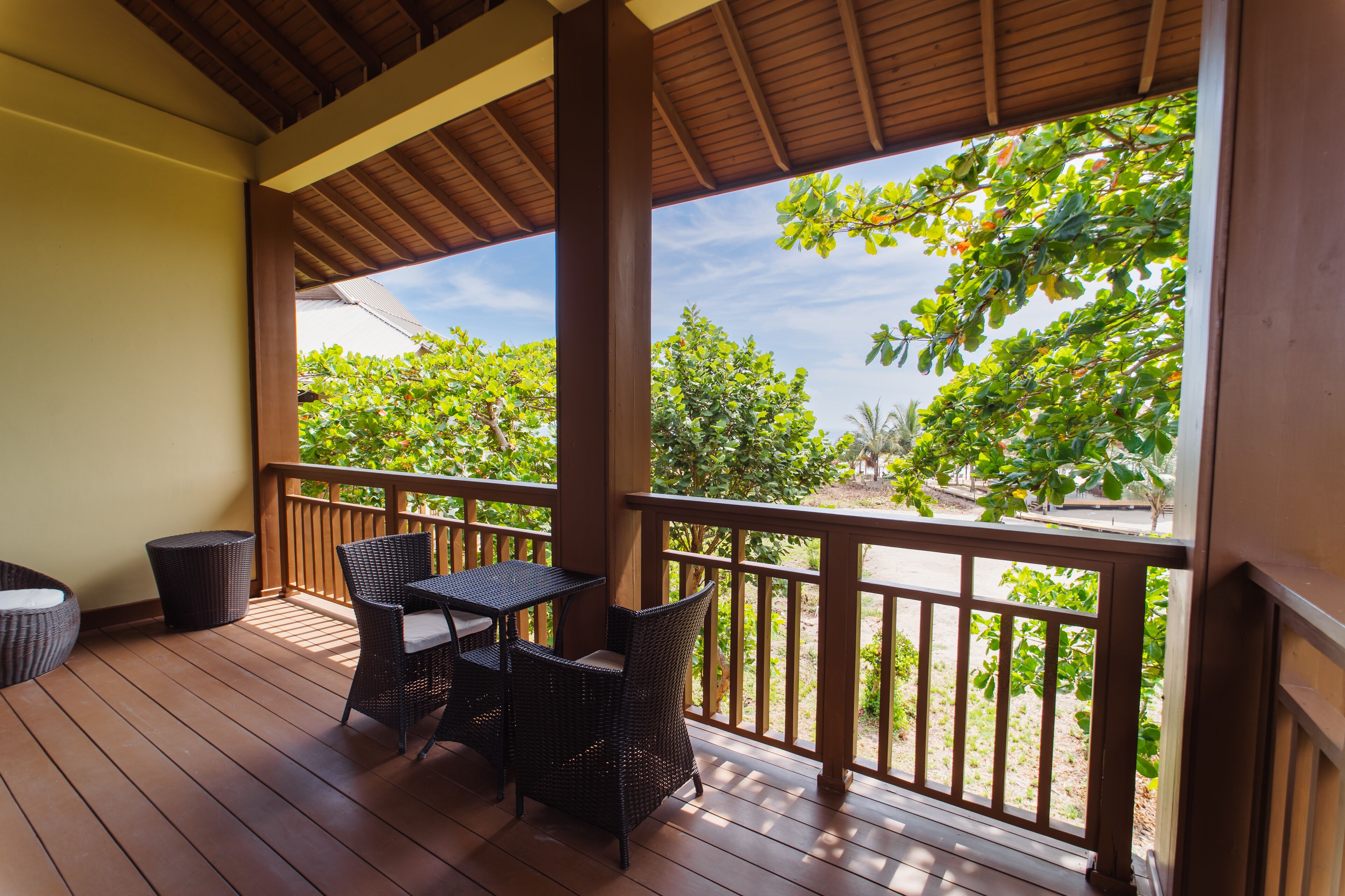 A wooden deck with wicker furniture and a view of greenery.