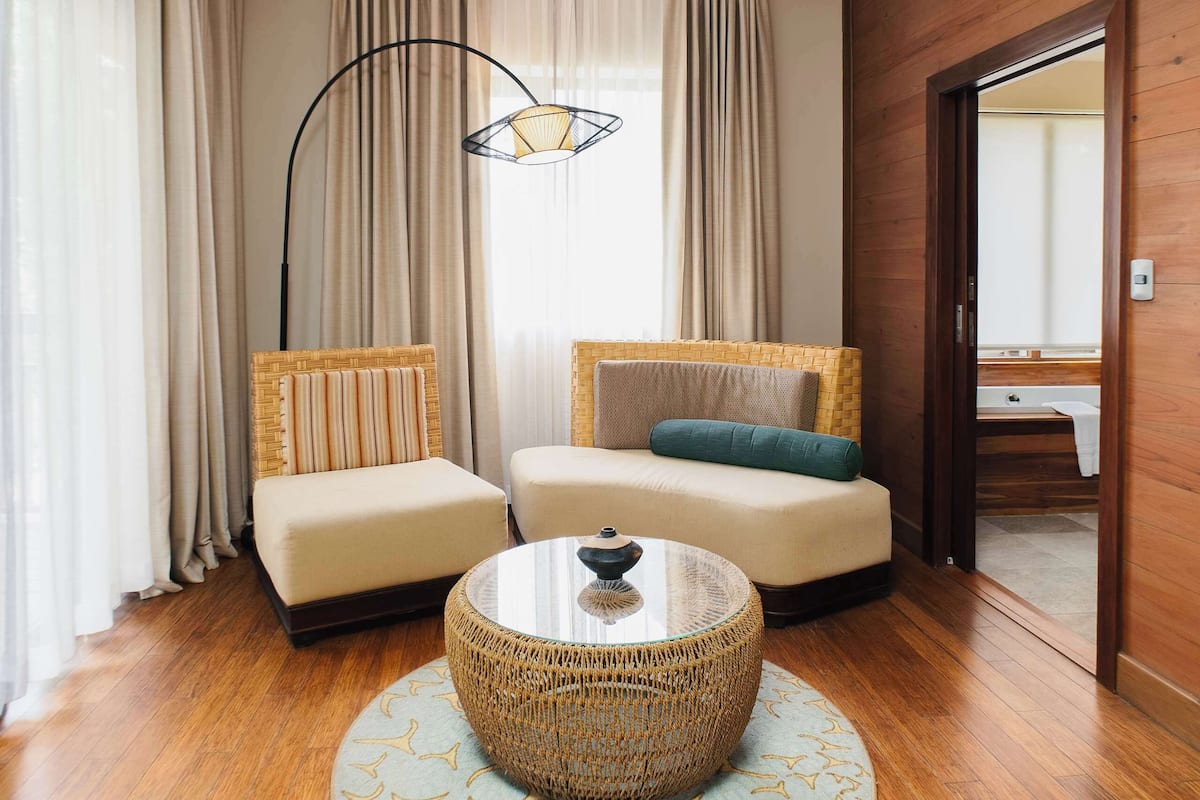 A modern living room with a sofa, a round coffee table, and a large window with curtains.