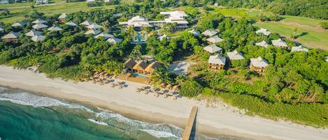 An aerial view of a resort with beachfront properties, a golf course, and a water body.