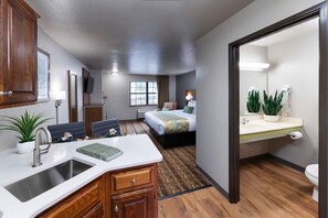 A compact hotel room with a kitchenette, a bed, a bathroom, and a small seating area. - Extended Stay Airport (Green Bay)