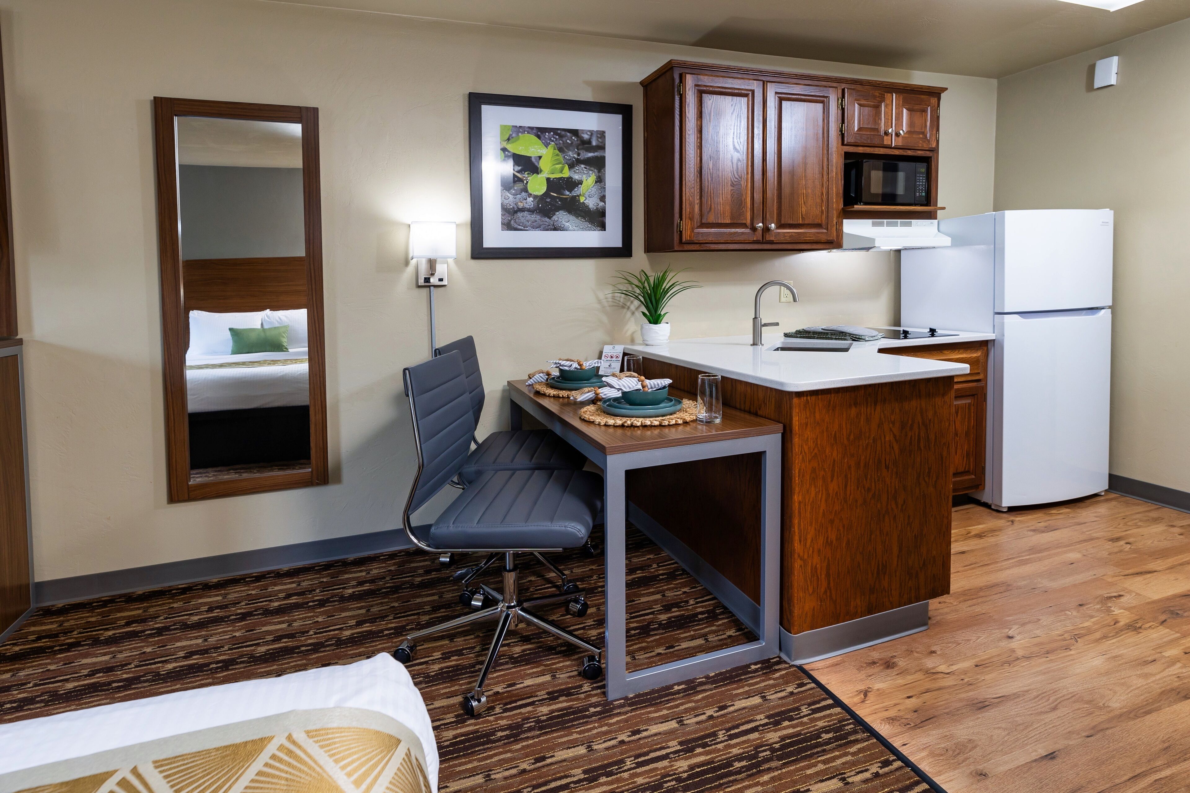 A compact kitchen with wooden cabinets, a microwave, and a refrigerator.