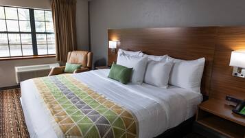 Habitación de hotel con una cama grande, una silla, una mesita de noche y una ventana con cortinas.