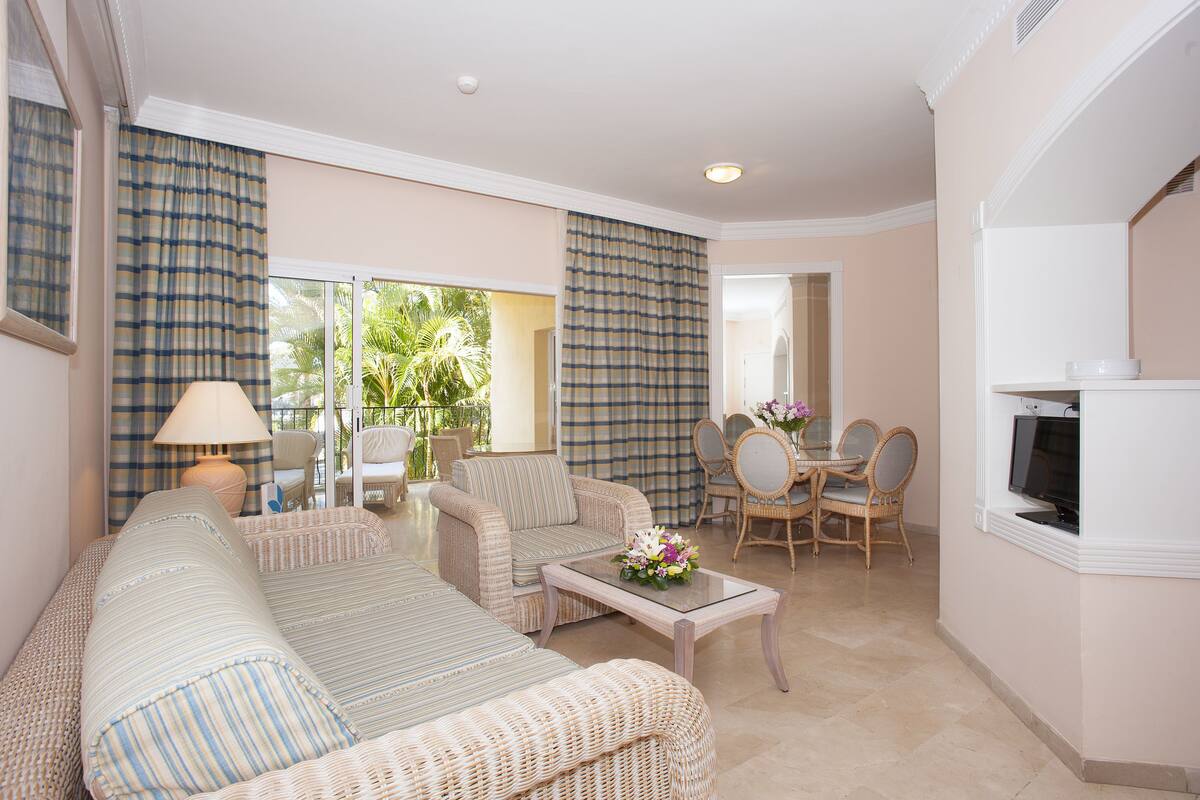 A living room with a sofa, armchairs, a coffee table, and a dining area with chairs and a table.