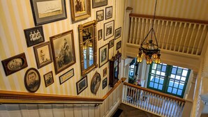 A staircase with a wooden handrail and a black carpeted landing. - Murray Hotel (Mackinac Island)