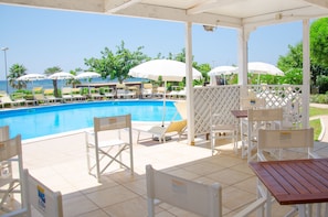 A poolside area with lounge chairs, umbrellas, and a view of the sea. - Villaggio Club Eden (Torricella)