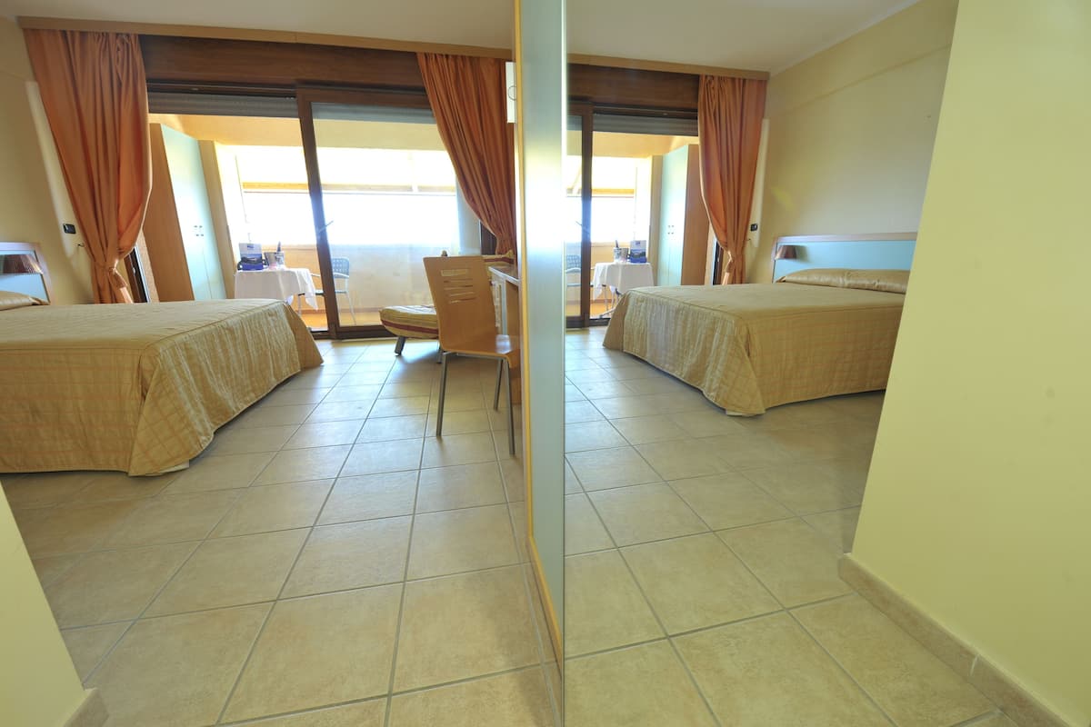 Habitación de hotel con dos camas, un escritorio y una silla.