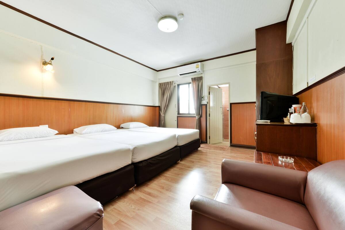 Hotellihuone, jossa on suuri sänky, televisio, työpöytä ja tuoli.
