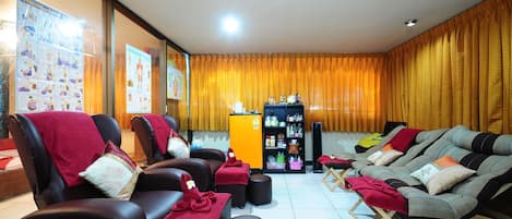 A massage room with leather chairs, red towels, and a small shelf with bottles.