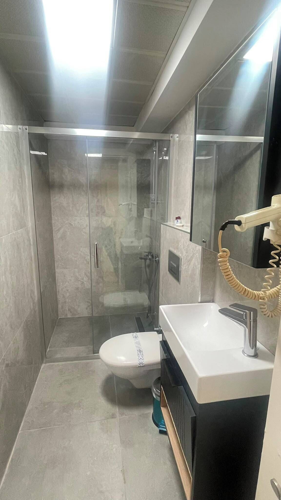 Een moderne badkamer met een douchecabine van glas, een toilet en een wastafel met spiegel.