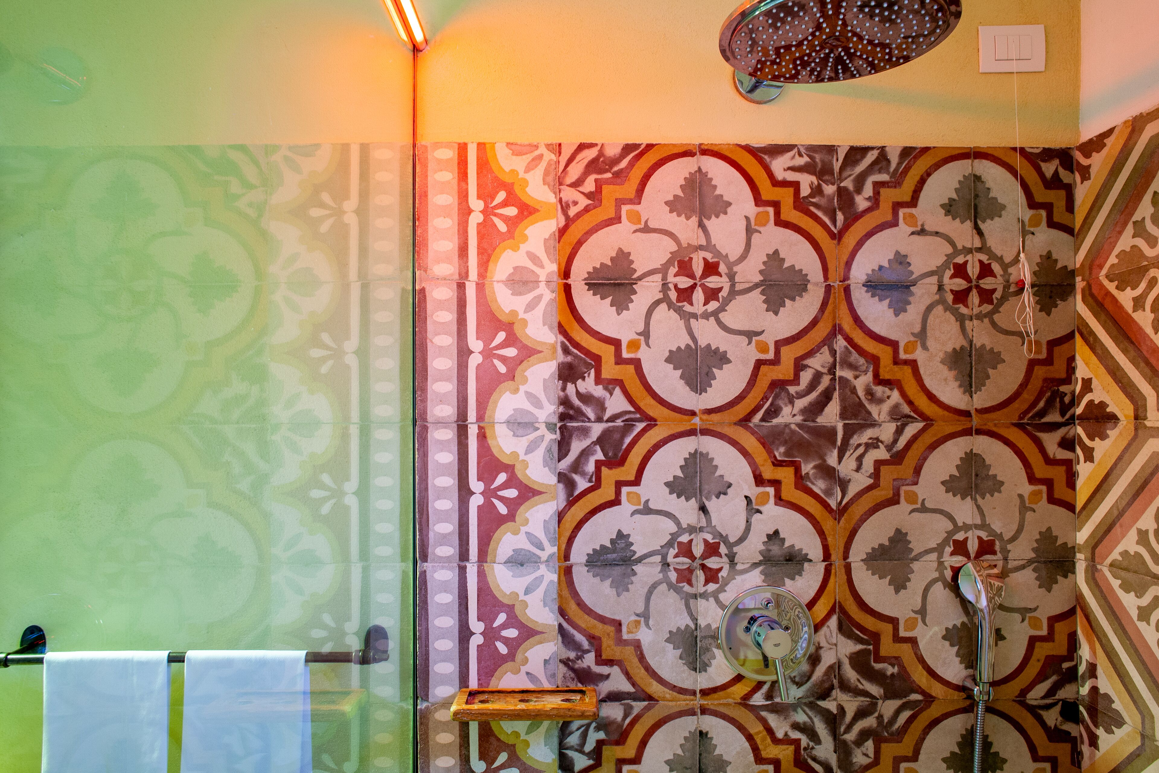 A bathroom with patterned tiles, a towel rack, and a shower.