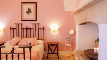 A bedroom with a bed, bedside table, wall-mounted light, and a fireplace.