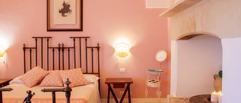 Une chambre à coucher comprenant un lit, une table de chevet, une lampe fixée au mur et une cheminée.