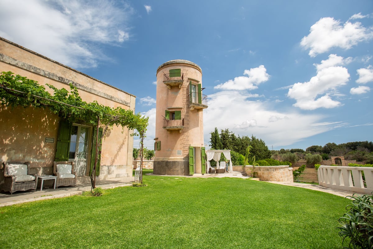 A building with a cylindrical tower, outdoor seating, and a well-maintained lawn.