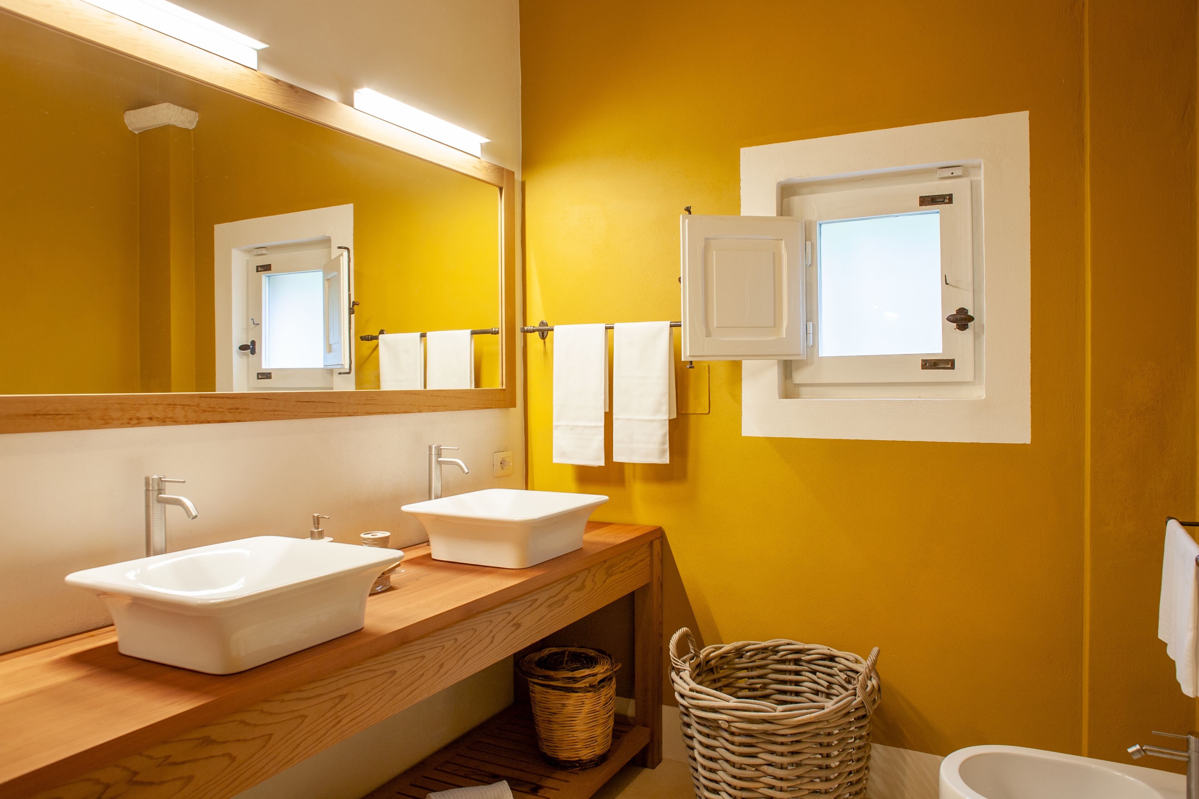Un baño con dos lavamanos, un espejo y una ventana.