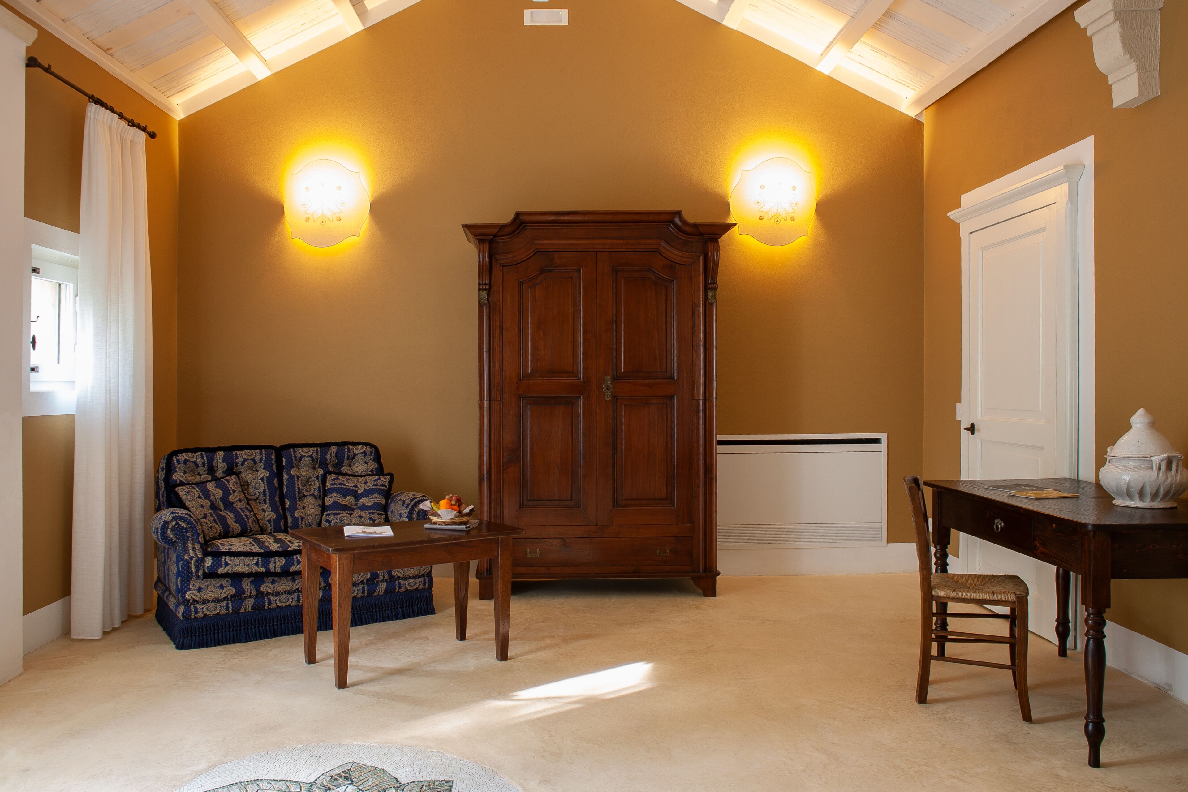 A room with a wooden cabinet, a sofa, a table, and a chair.