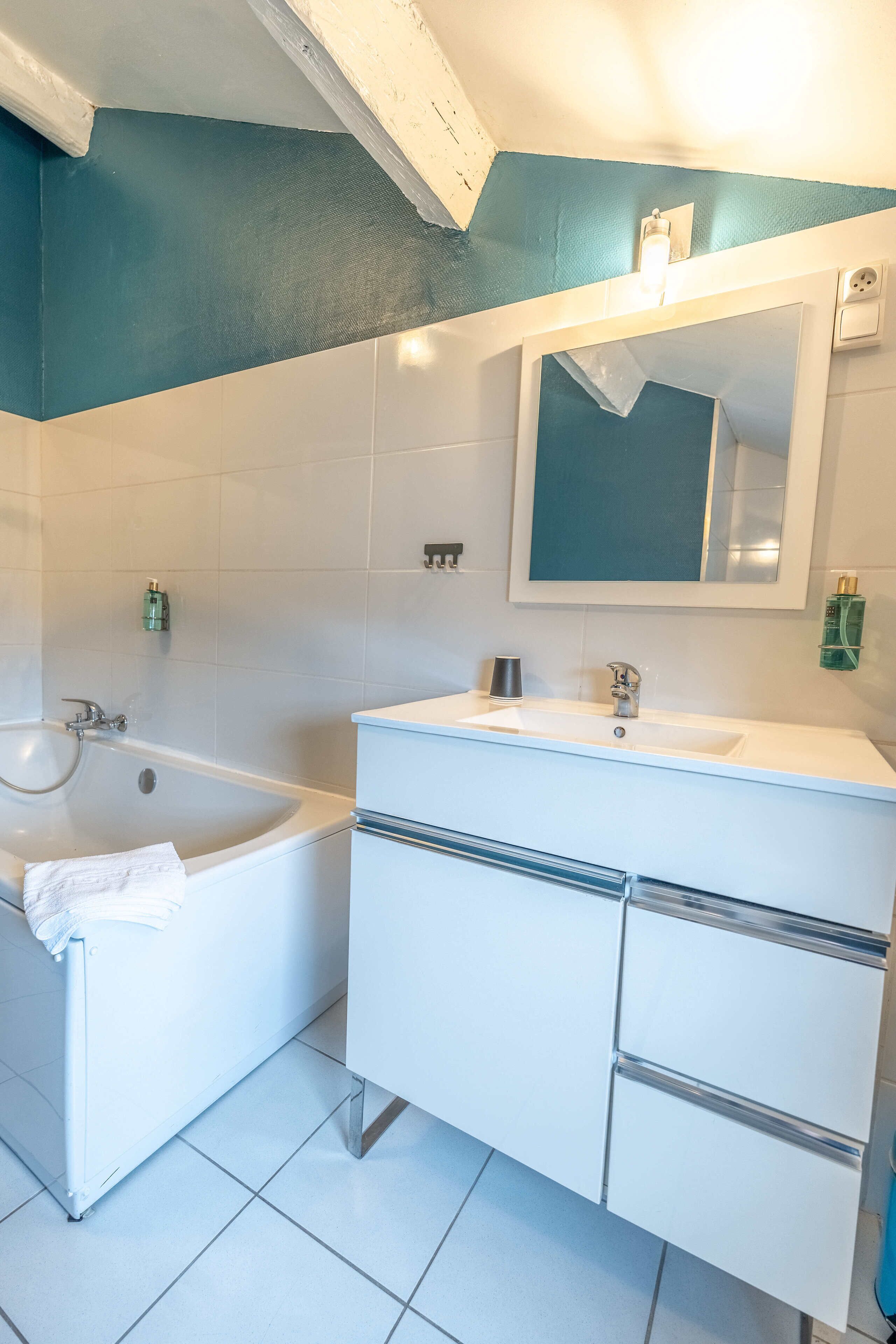 Un bagno con una vasca, un lavandino e uno specchio.