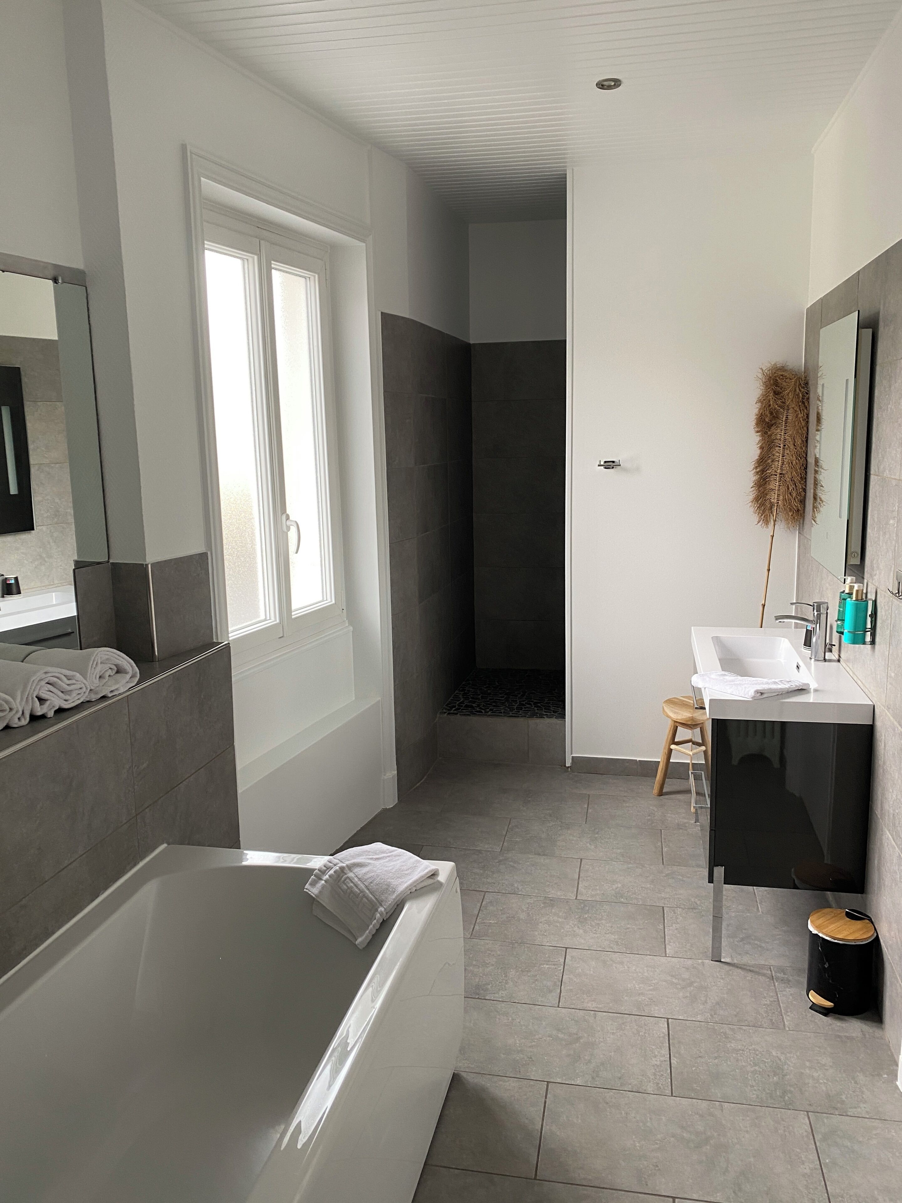 Un baño moderno con bañera, ducha, tocador con espejo y retrete.