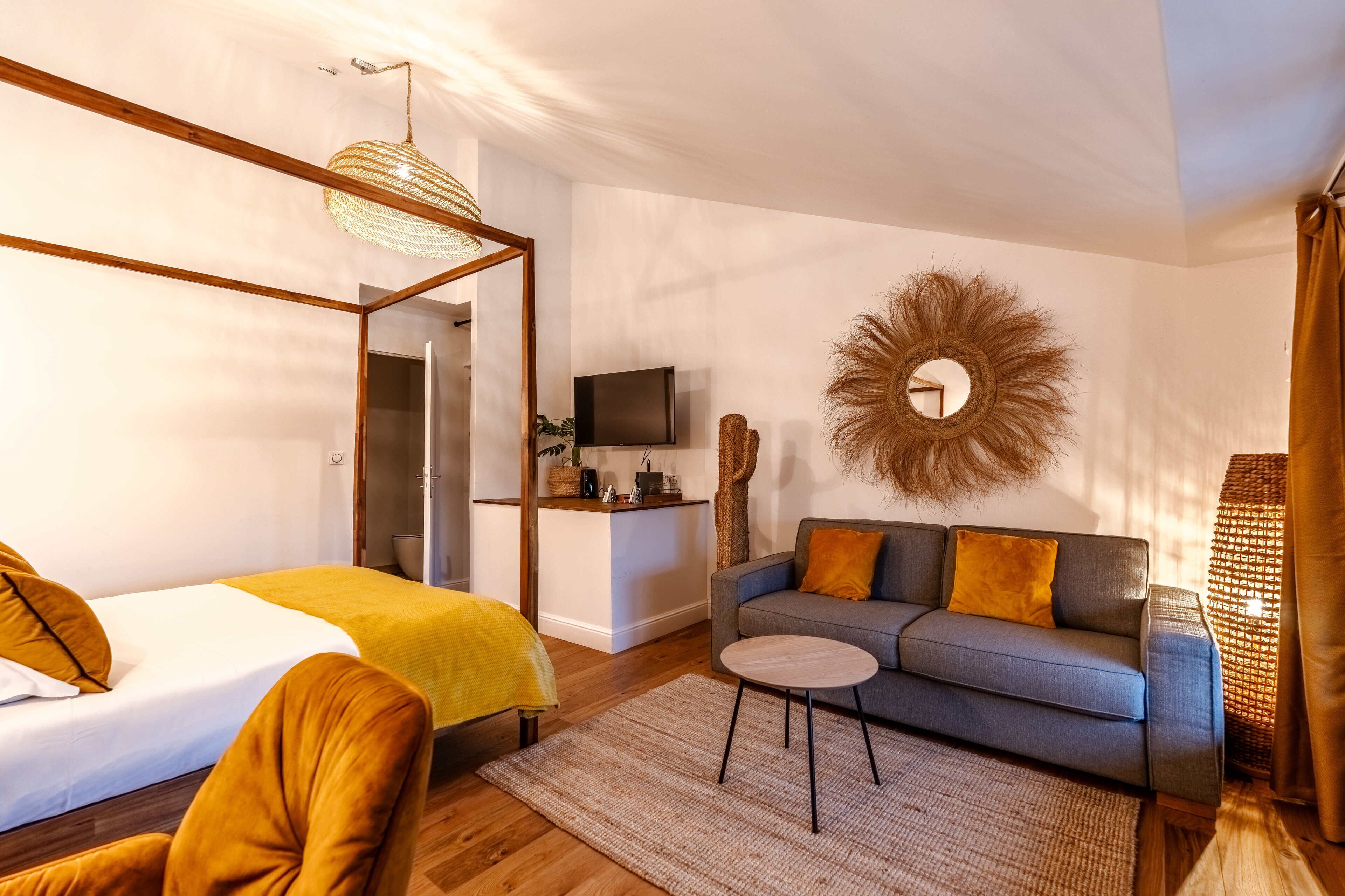 Una habitación de hotel moderna con una cama, un sofá, un televisor y un espejo decorativo.