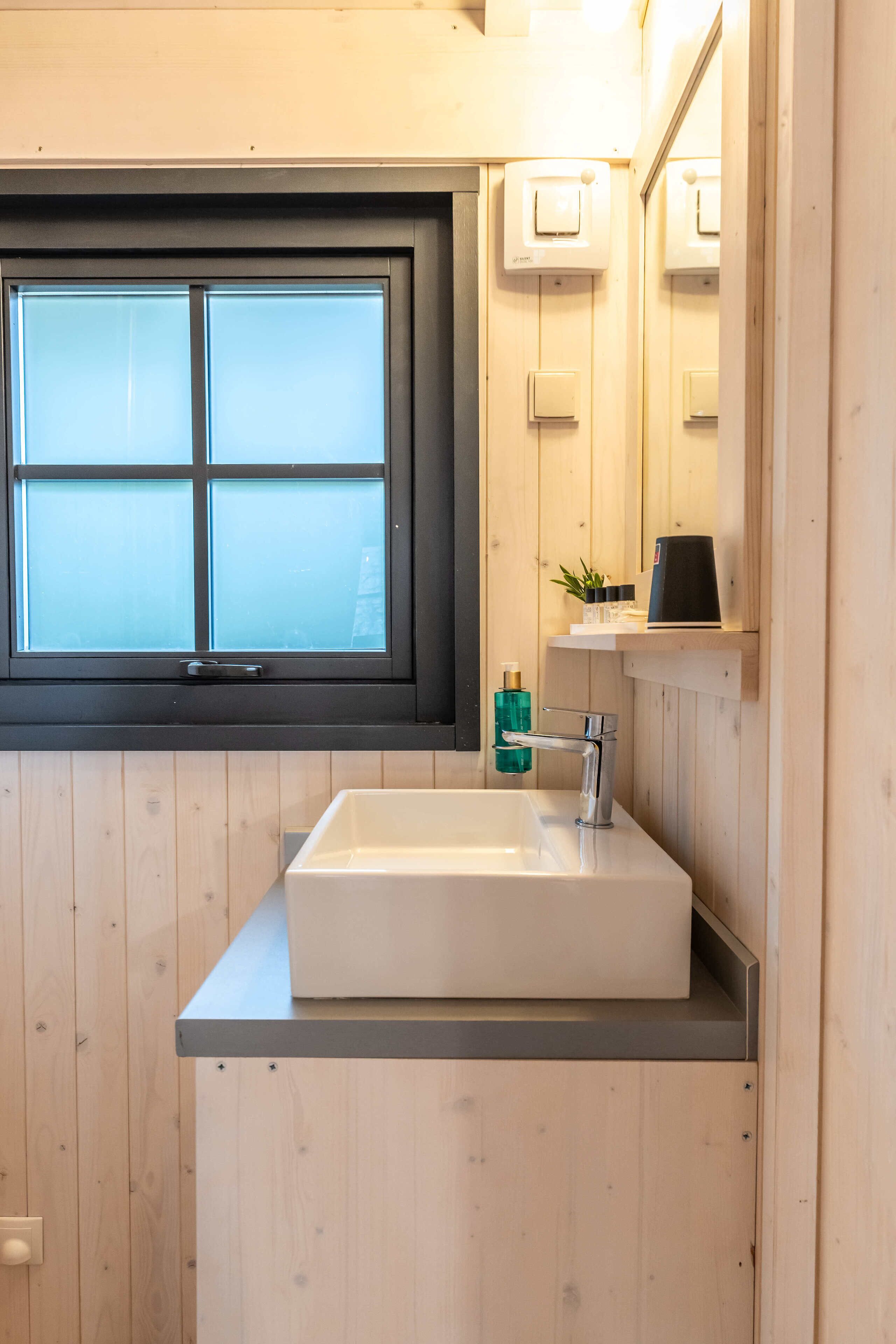 A bathroom with a window, a sink, and a mirror.