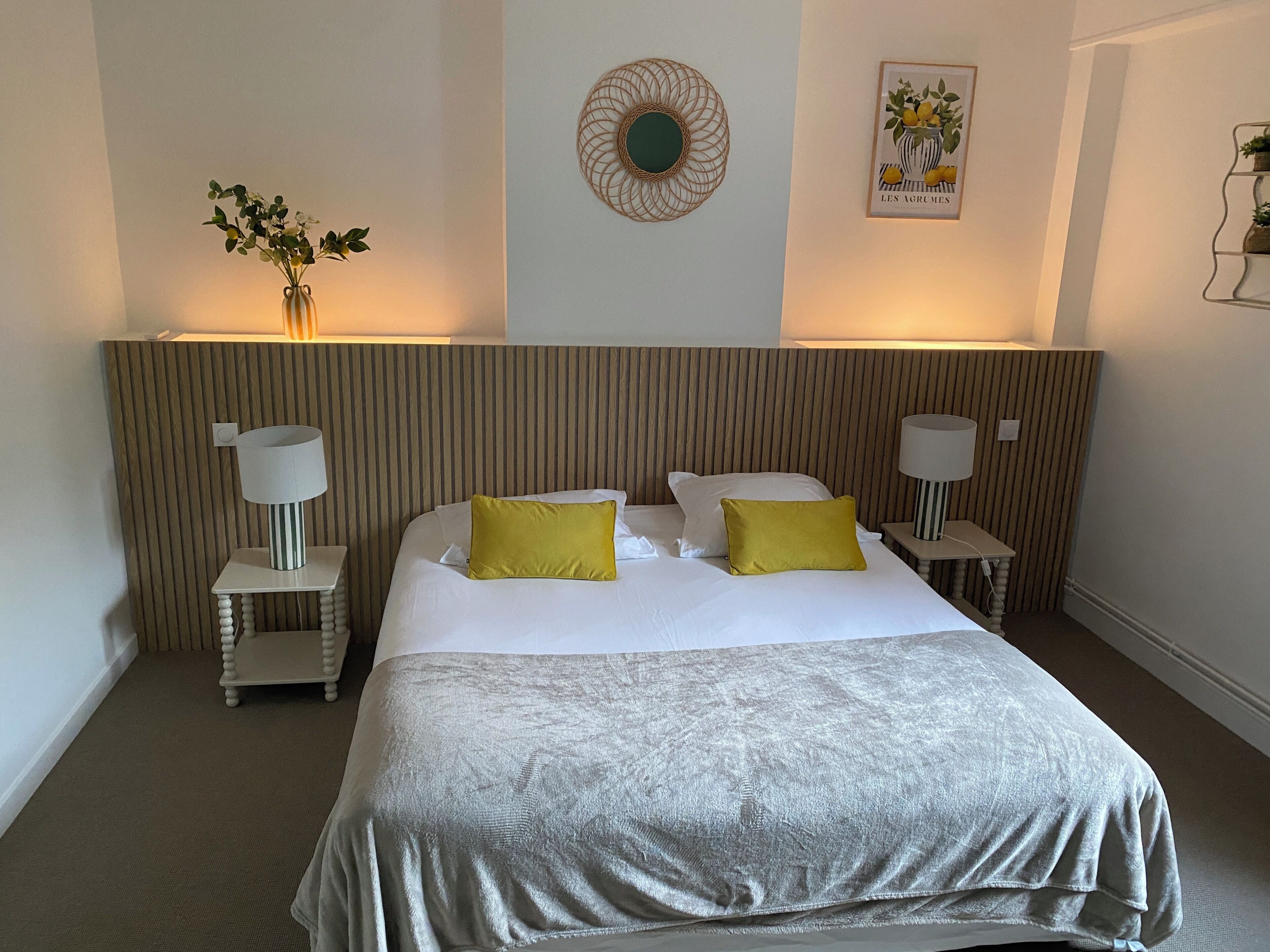 Een hotelkamer met een groot bed, twee nachtkastjes met lampen, een decoratieve wandversiering en een ingelijst beeld.