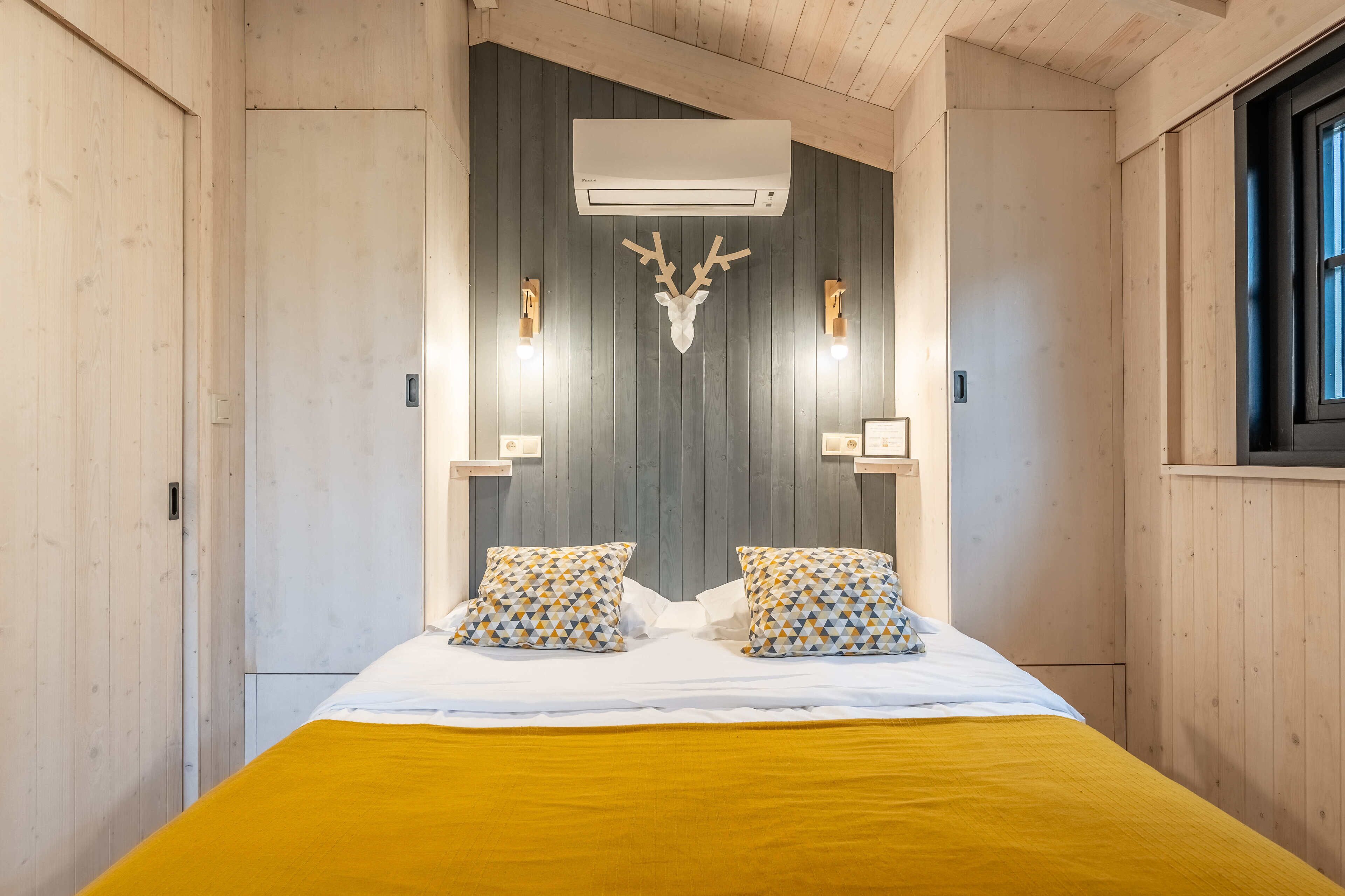 Une chambre à coucher avec un lit, un climatiseur fixé au mur et une décoration représentant une tête de cerf.