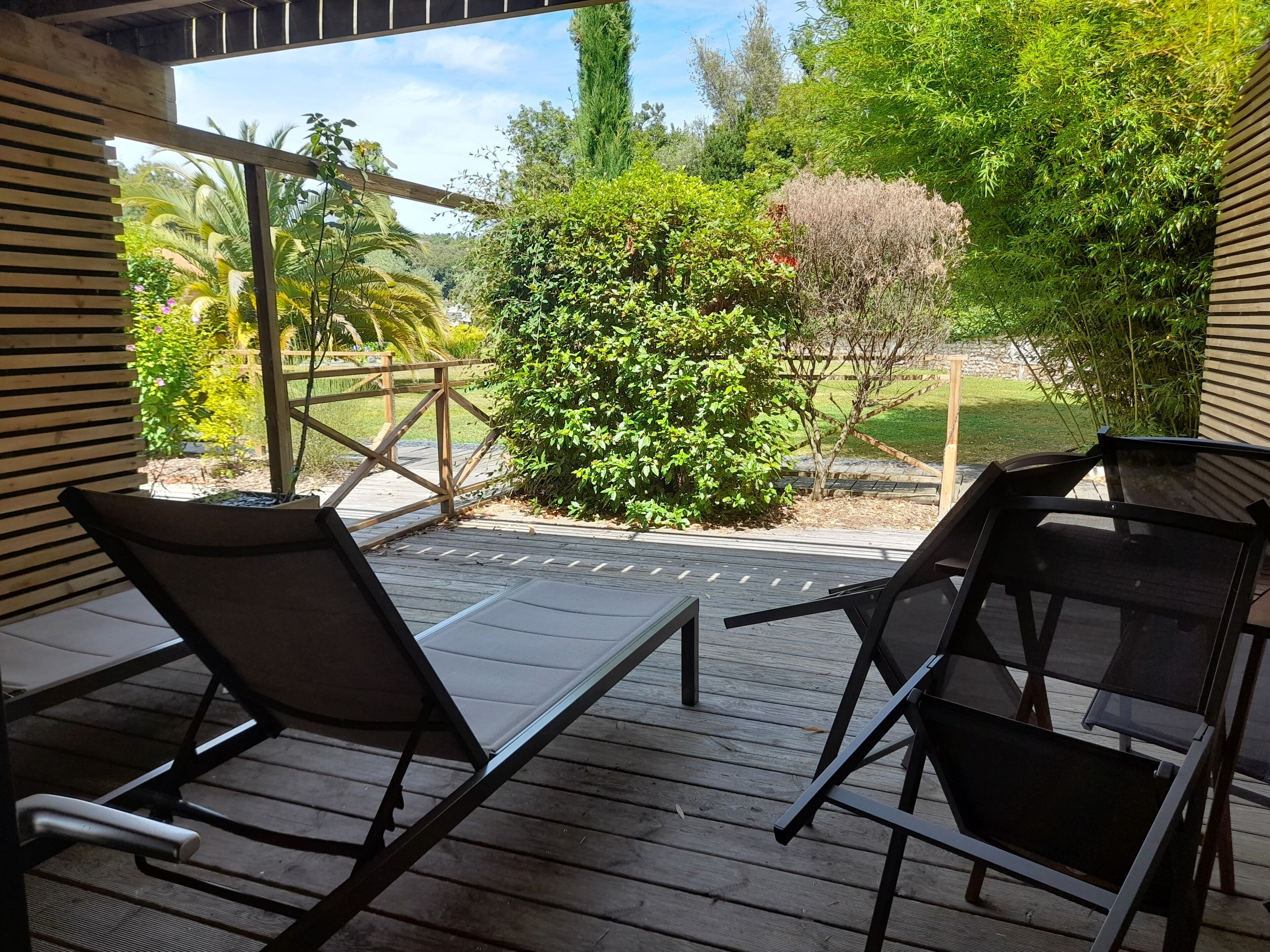 A wooden deck with two lounge chairs facing a garden.