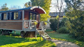 Situated in a serene grassy area, this home offers a cozy porch and a ladder leading up to the entrance.