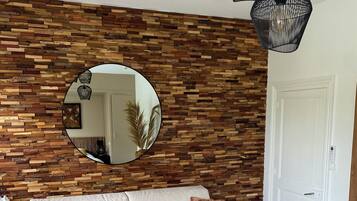 Una habitación con un sofá blanco, dos mesas redondas de madera, un espejo y una pared de madera.