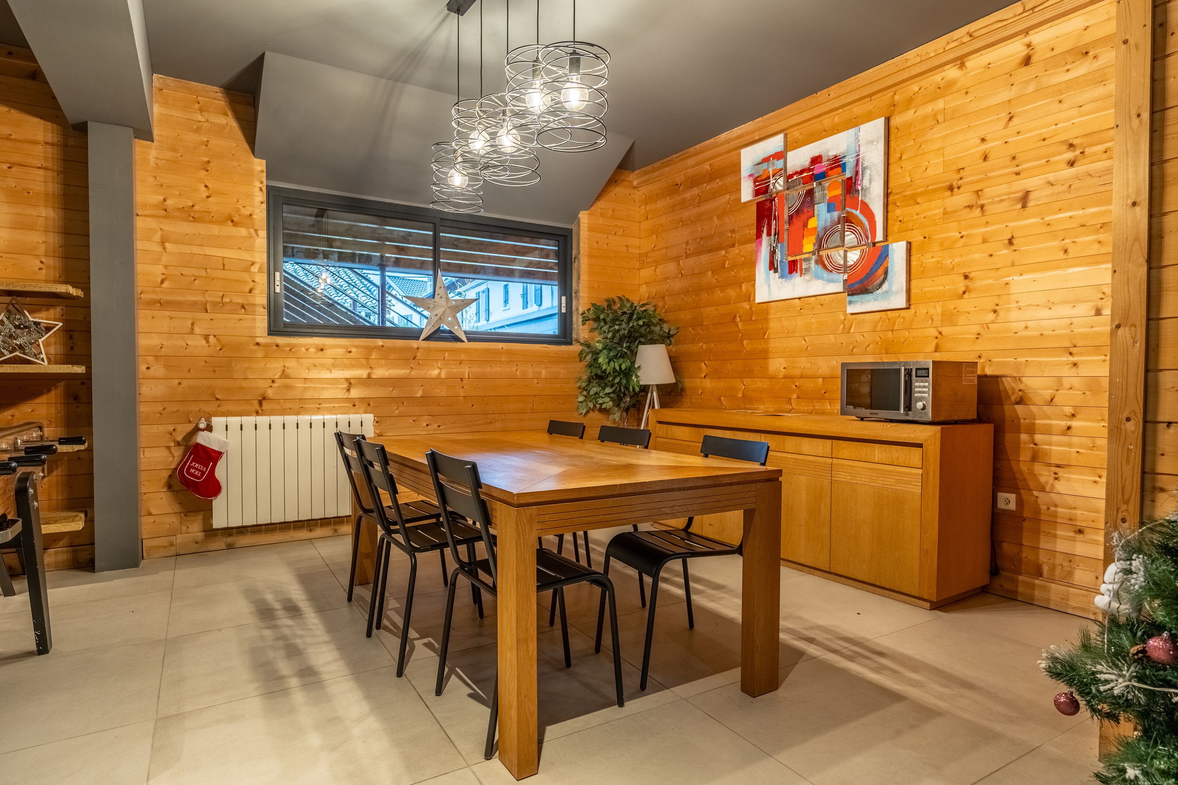 Una cocina moderna con paredes de madera, una mesa de comedor con sillas, un microondas y una ventana con persianas.