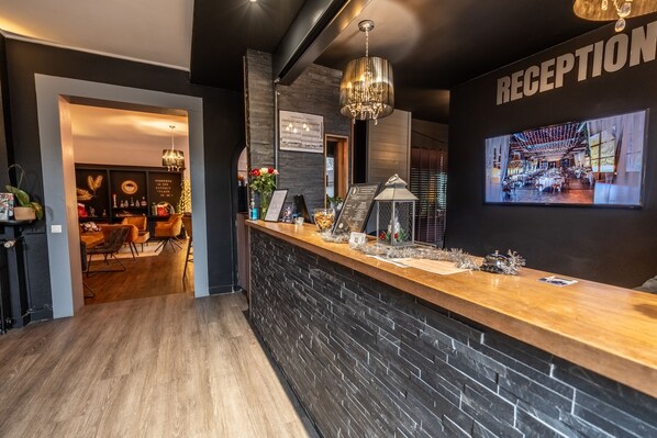 A reception area with a wooden counter, a chandelier, and a 'RECEPTION' sign. - Hôtel Quai des Pontis (Cognac)