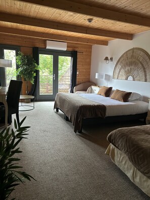 A bedroom with a bed, a desk, and a chair. There is a window with a view of greenery outside. - Hôtel Quai des Pontis (Cognac)