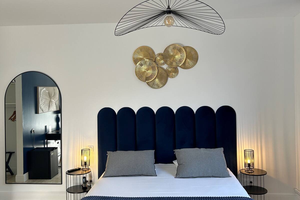 A modern bedroom with a large bed, a unique ceiling light, and a mirror.