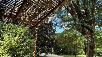 A wooden pergola structure with a metal fence in a park.