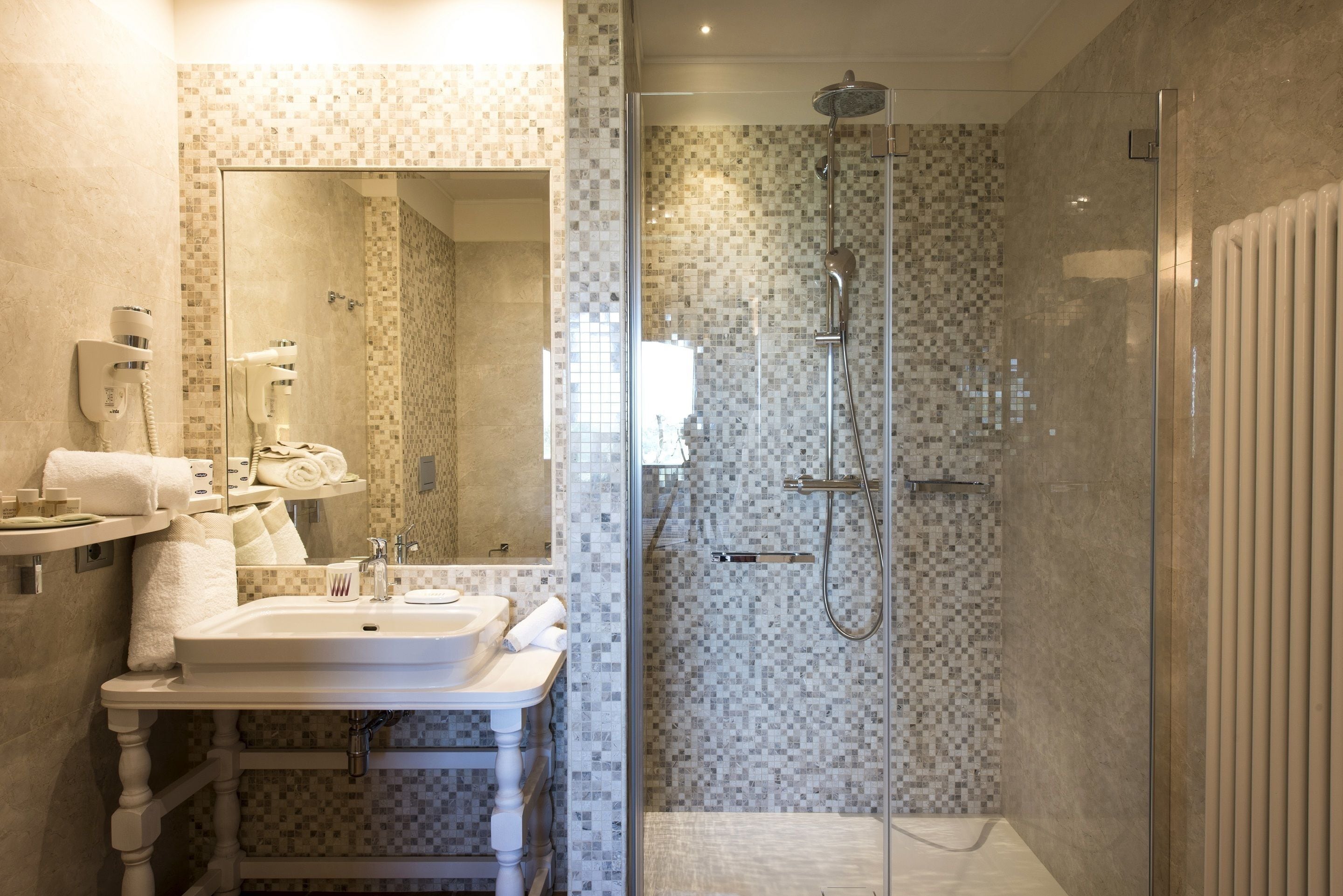 Un baño moderno con ducha de vidrio, lavabo con espejo y un perchero para toallas.