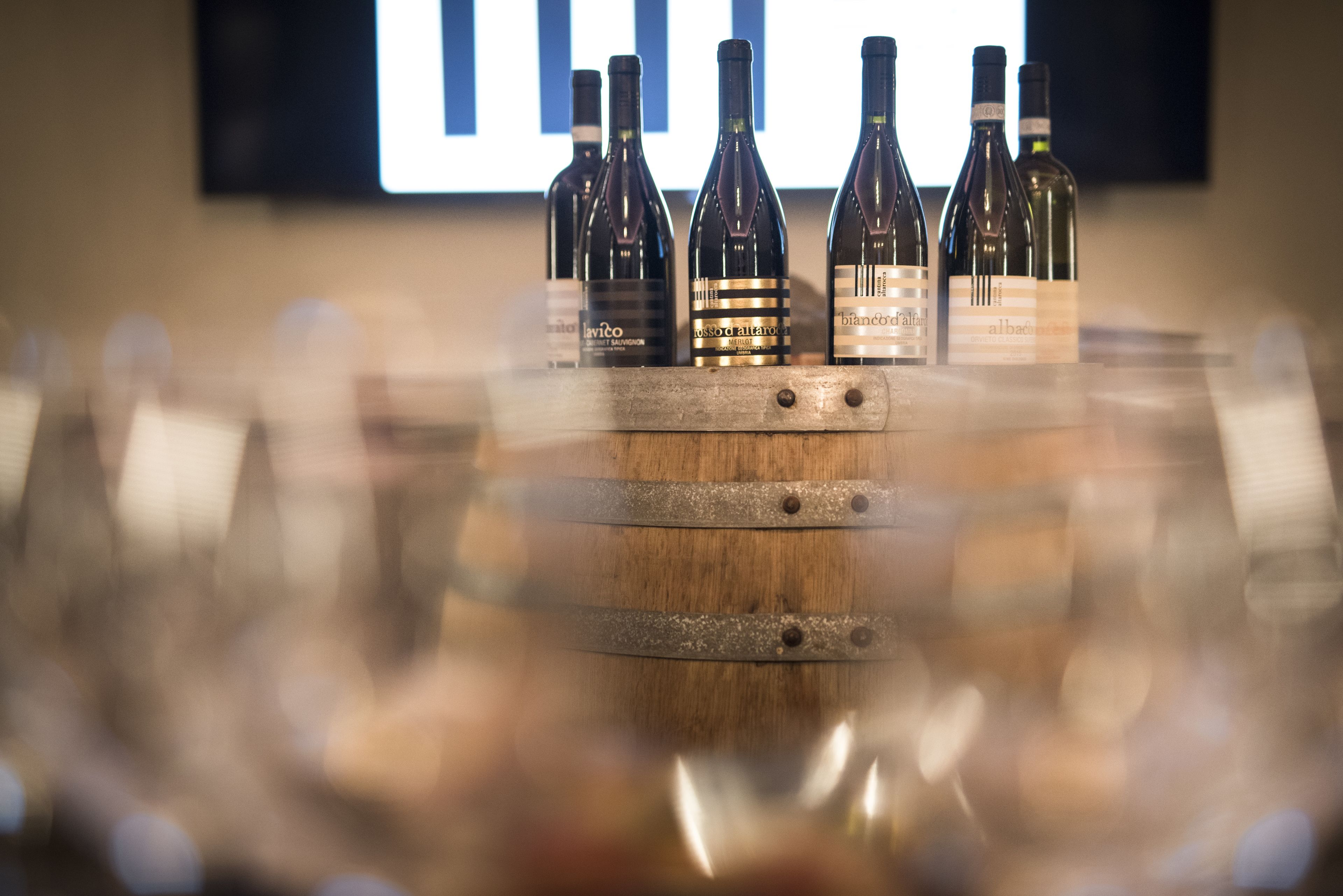 A wooden barrel with wine bottles labeled 'Lavito', 'Bianchi', and 'Albaceta' on top.