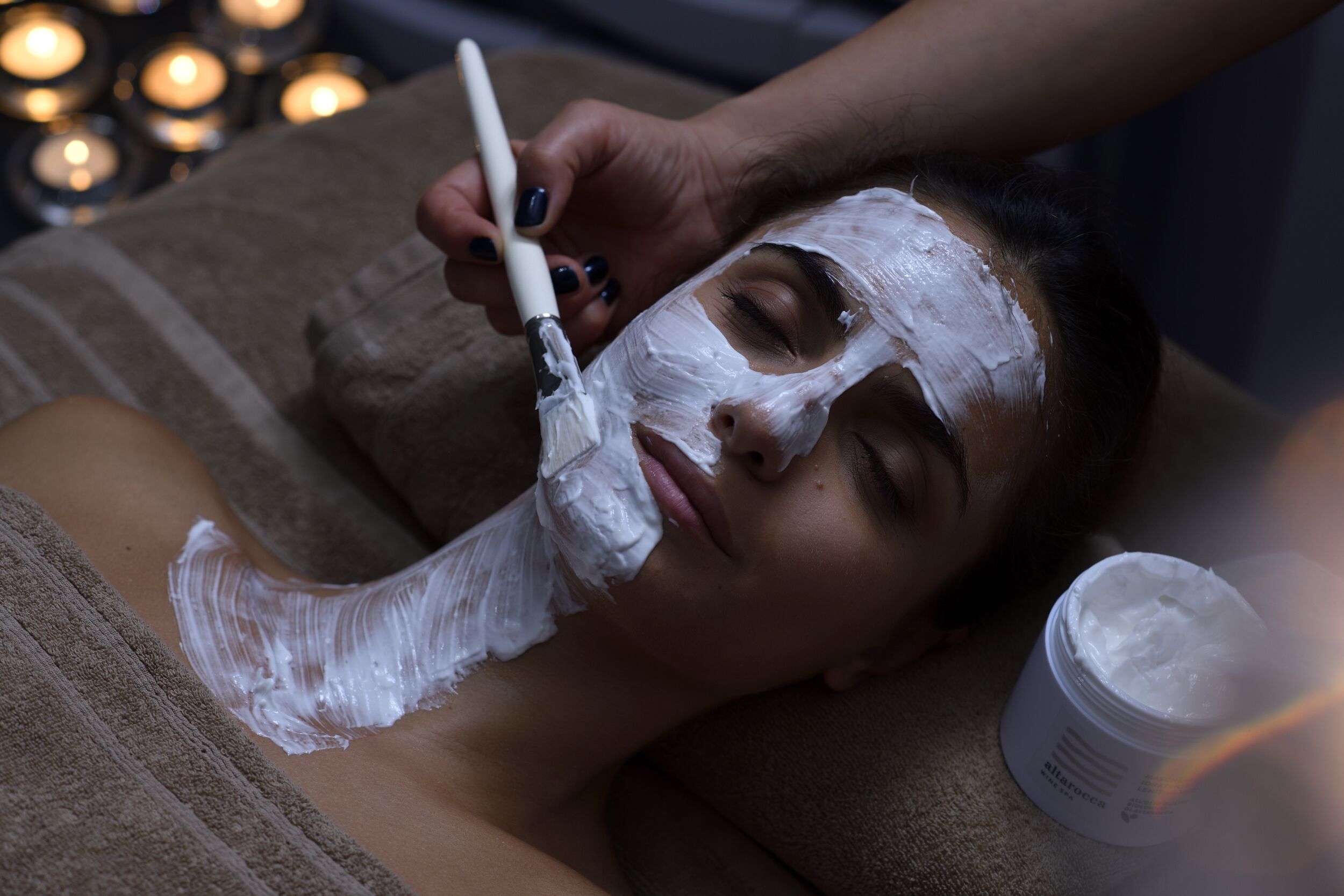 A person receiving a facial treatment with a white cream.
