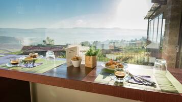 Ein Frühstückstisch mit Gebäck, Kaffee und einer Speisekarte auf einem Balkon mit Blick auf eine reizvolle Landschaft.