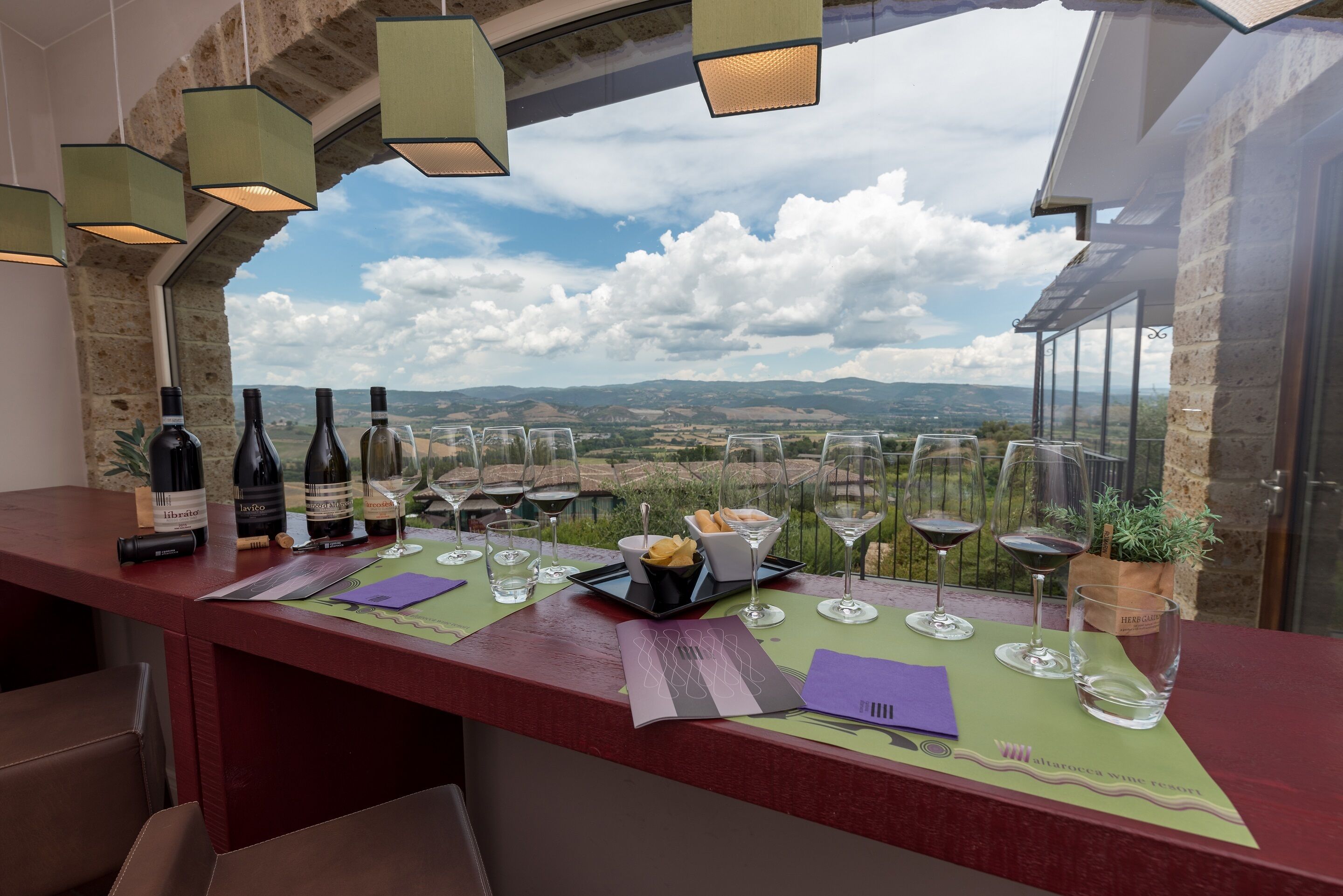 A wine tasting setup with bottles, glasses, and a view of the countryside.
