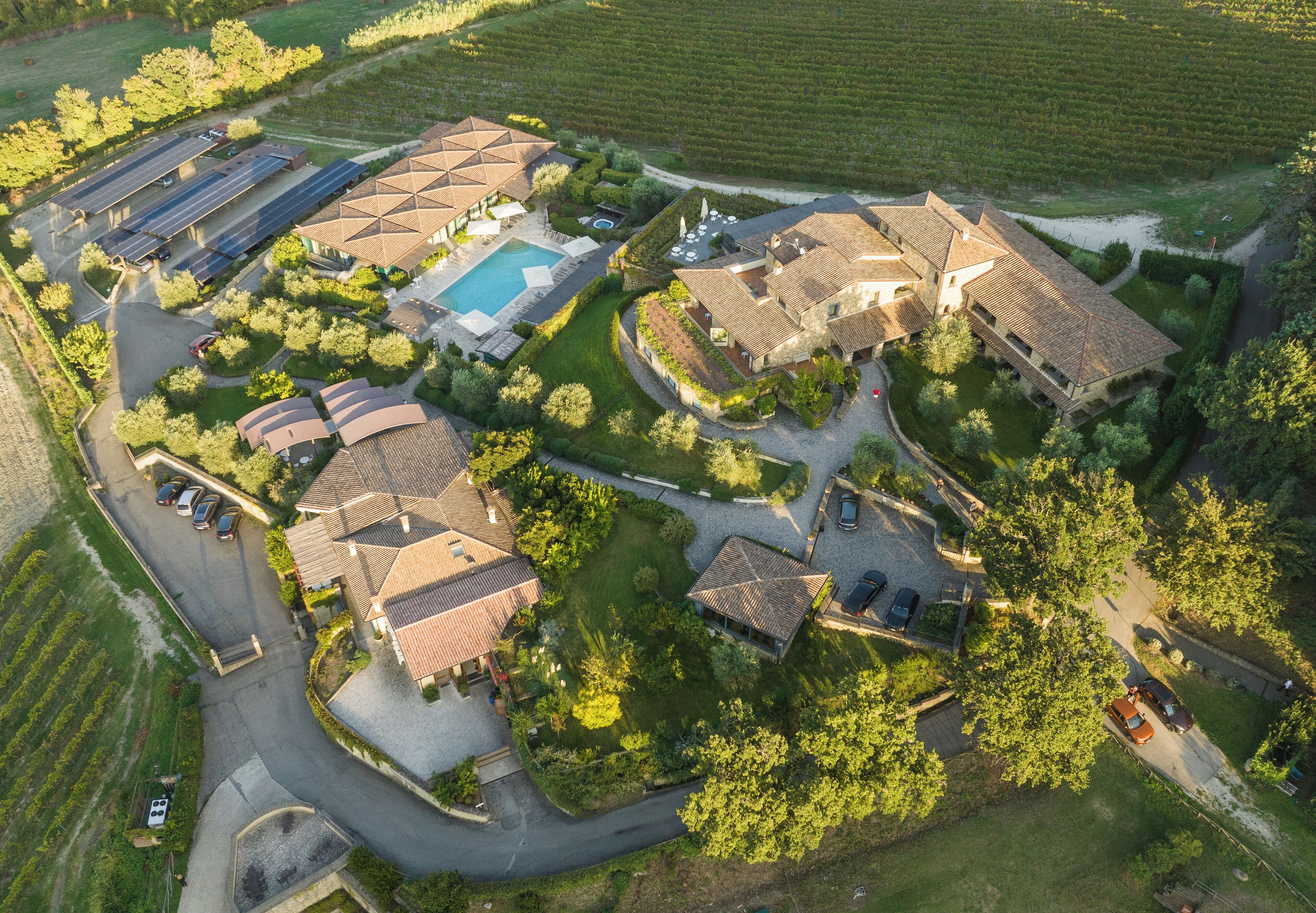 Vista aérea de una propiedad residencial con varios edificios, una piscina y un área de estacionamiento.