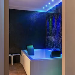 Relax in a serene spa room with a large hot tub and a comfortable chair.