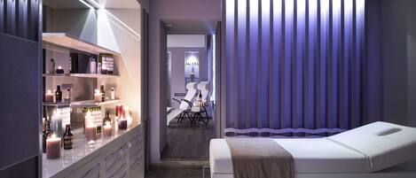 Une chambre moderne équipée d’un lit, d’une coiffeuse avec des articles de toilette et d’un fauteuil de massage.