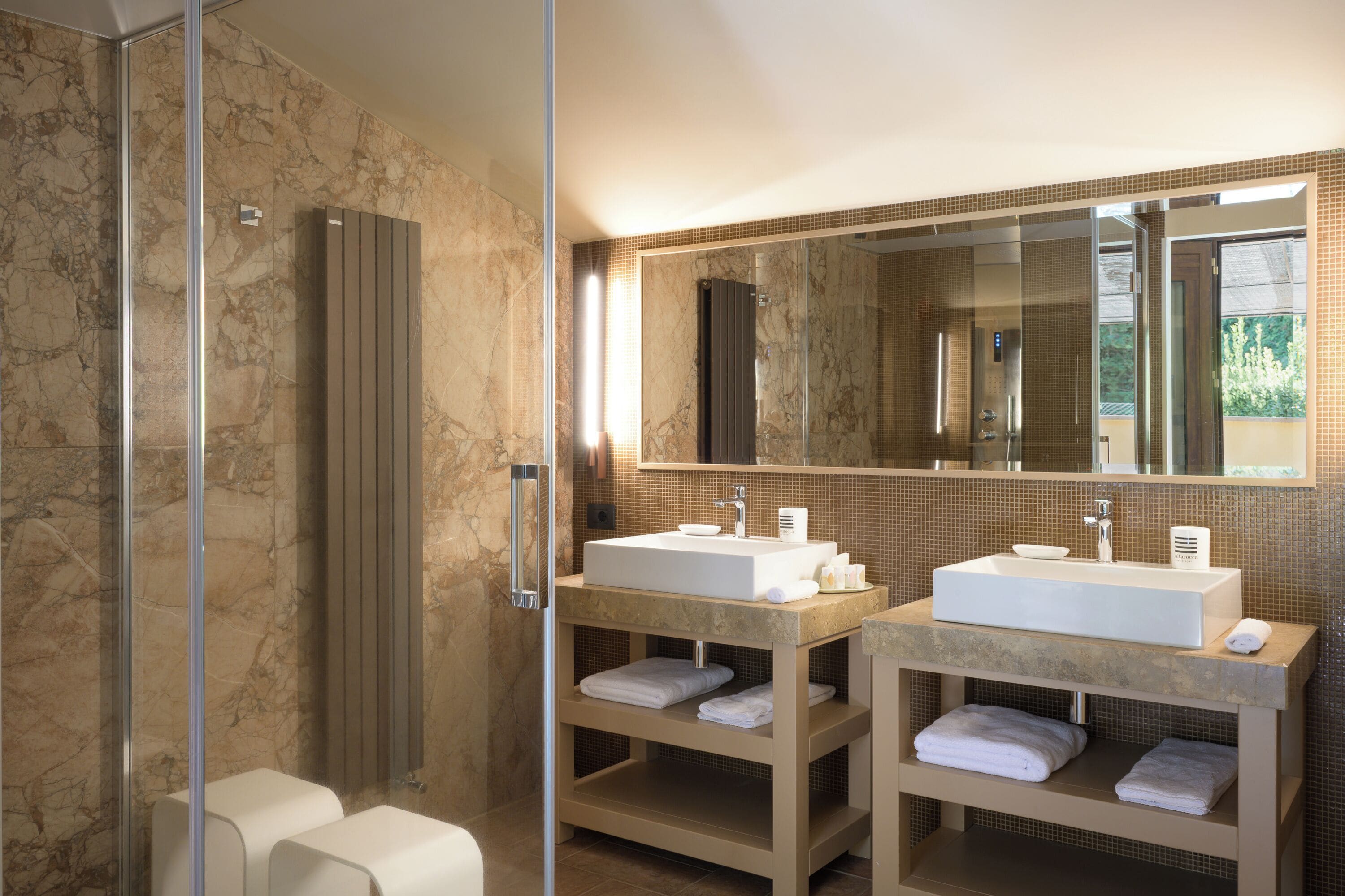 Une salle de bain moderne avec deux lavabos, un grand miroir et une douche à l’italienne.