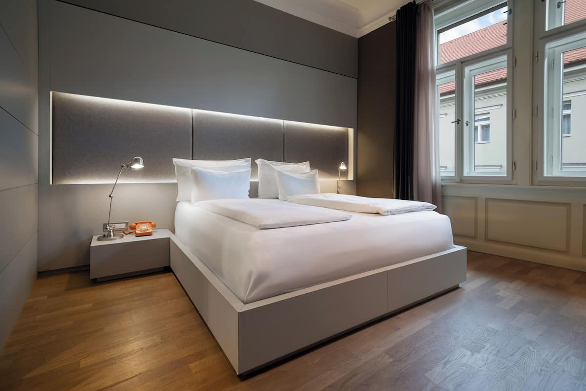 A modern bedroom with a large bed, bedside tables, and a window with curtains.