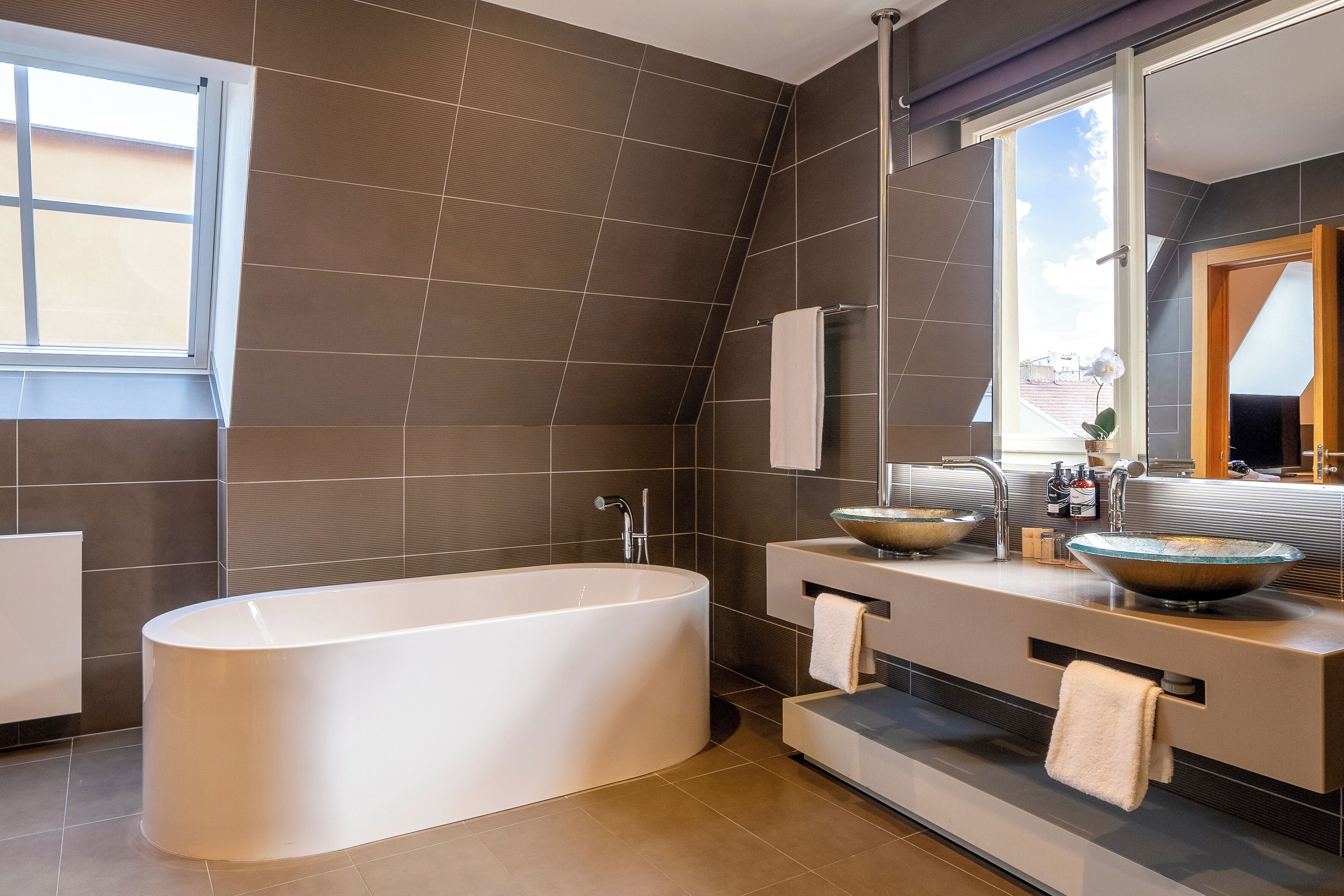 Un baño moderno con una bañera independiente, un espejo grande y un tocador con lavabo.