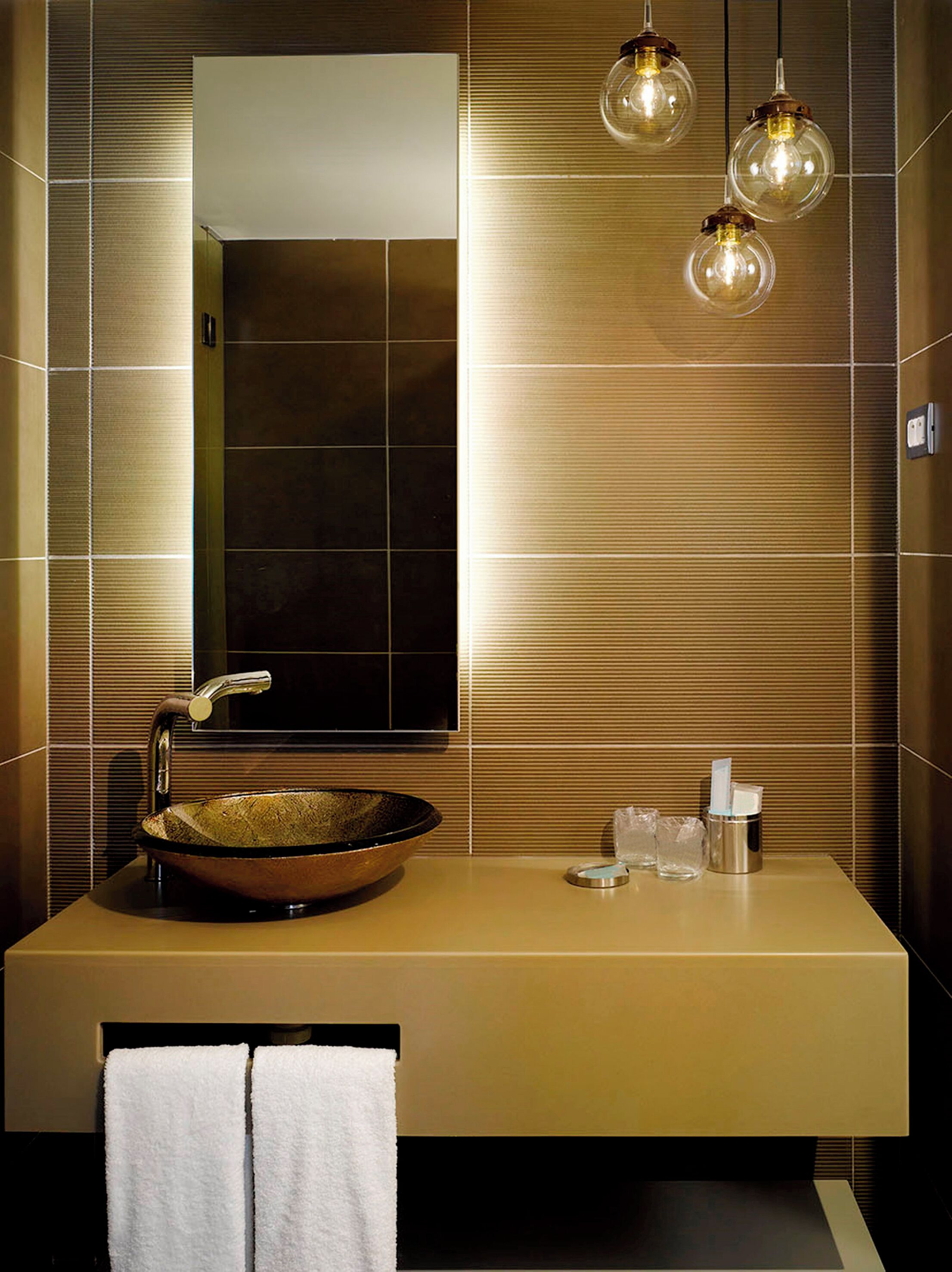 A modern bathroom with a large mirror, a vessel sink, and three hanging pendant lights.