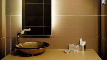 A modern bathroom with a large mirror, a vessel sink, and three hanging pendant lights.