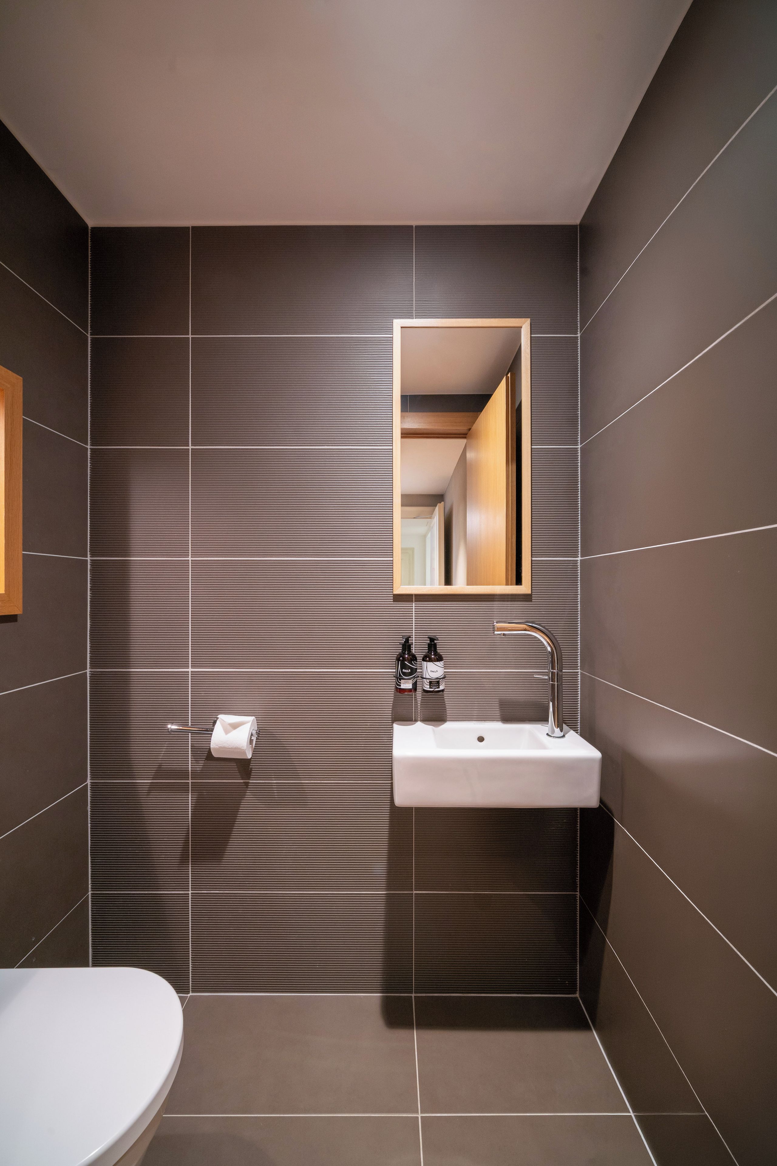 A modern bathroom with a white sink, a mirror, and a toilet.