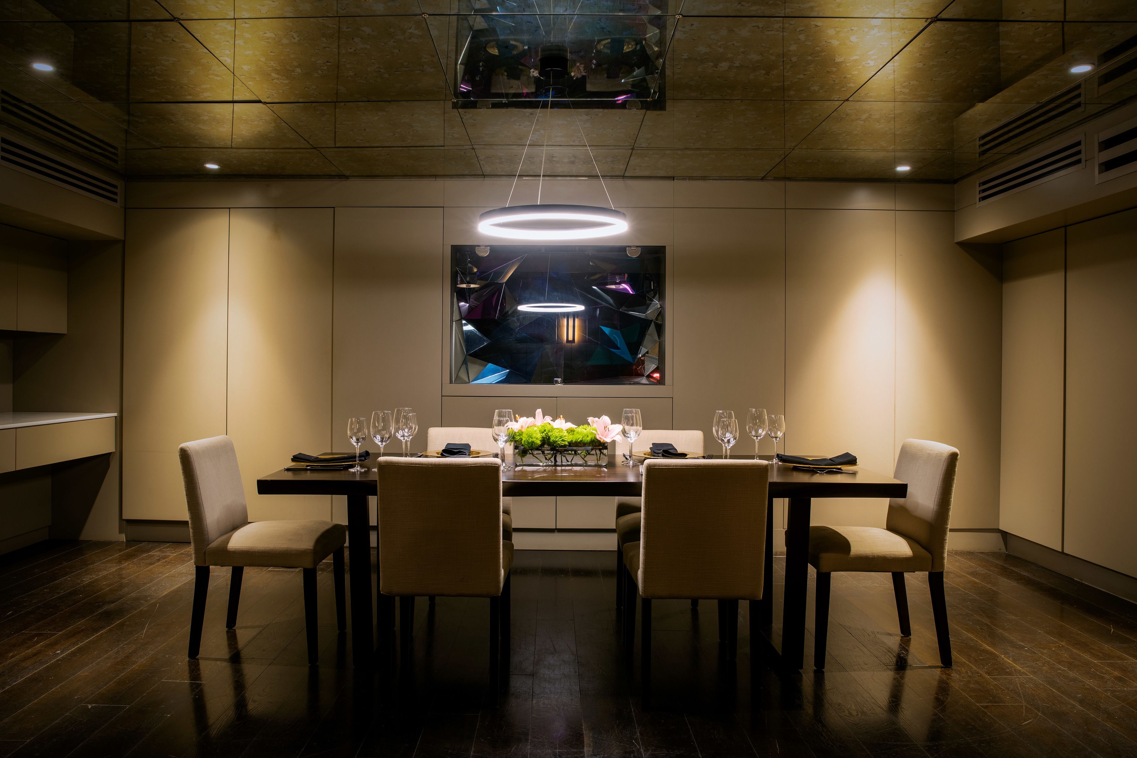 A dining area with a long table, four chairs, and a modern chandelier.