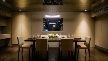 A dining area with a long table, four chairs, and a modern chandelier.